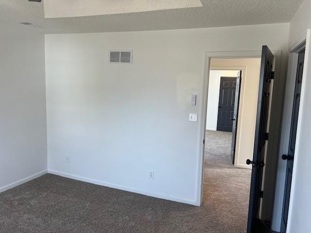 spare room with visible vents, dark carpet, a textured ceiling, and baseboards