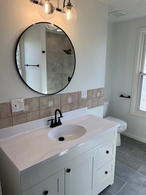 bathroom with vanity, visible vents, tile patterned floors, toilet, and tasteful backsplash