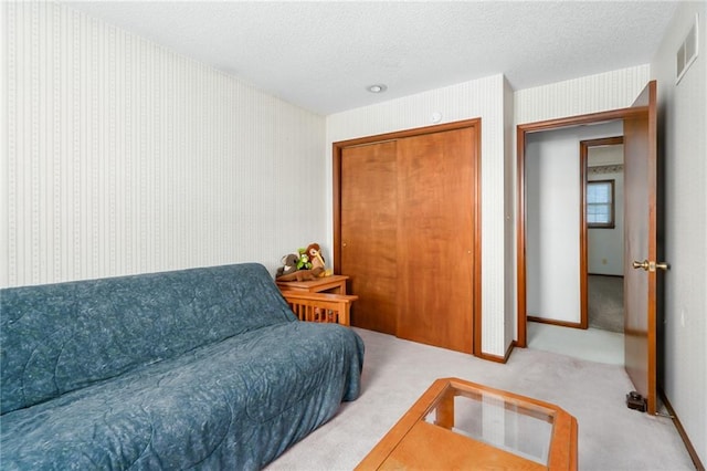 bedroom with baseboards, visible vents, carpet floors, wallpapered walls, and a textured ceiling