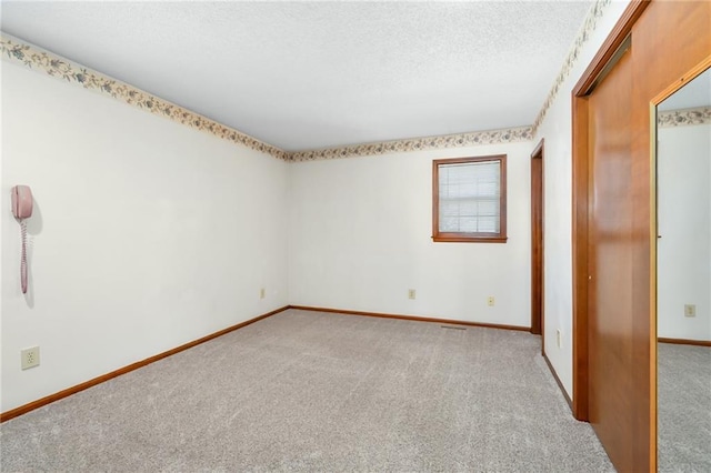 unfurnished bedroom with baseboards, a textured ceiling, and carpet