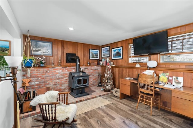 living area with recessed lighting, wooden walls, wood finished floors, and a wood stove