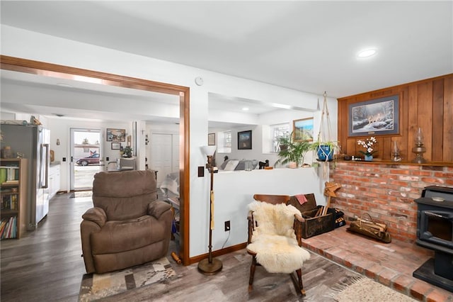 living area with wooden walls, wood finished floors, and a wood stove