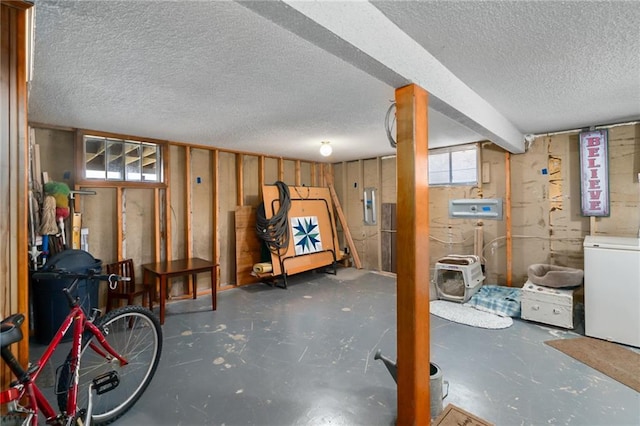 below grade area with fridge, electric panel, and a textured ceiling