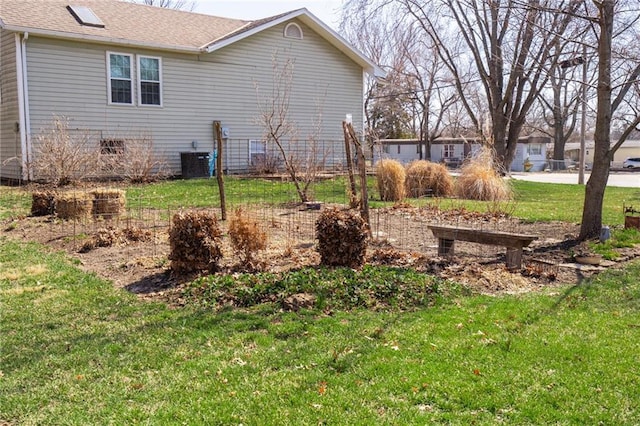 exterior space with cooling unit, a shingled roof, and a yard