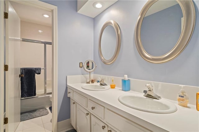 full bath with tile patterned flooring, double vanity, bath / shower combo with glass door, and a sink