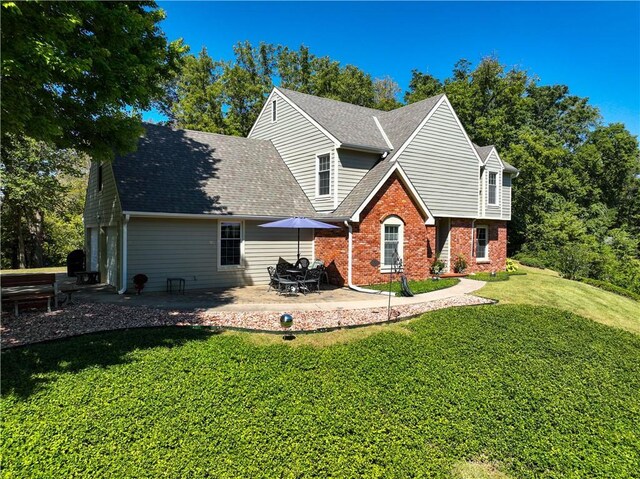 back of property with brick siding, a yard, roof with shingles, and a garage