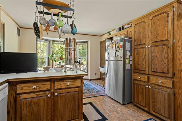 kitchen featuring brown cabinets, crown molding, light countertops, and freestanding refrigerator