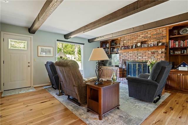 living room featuring beamed ceiling, baseboards, wood finished floors, and a fireplace
