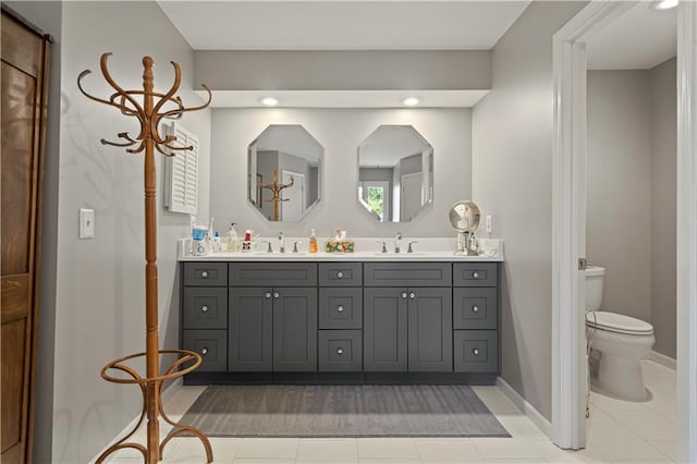 bathroom with toilet, tile patterned floors, double vanity, and a sink