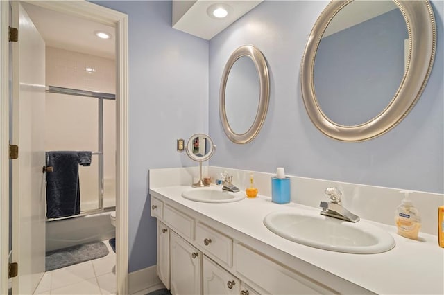 full bathroom featuring shower / bath combination with glass door, double vanity, tile patterned flooring, and a sink