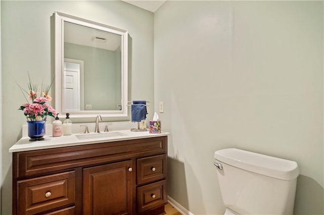 half bathroom featuring visible vents, toilet, and vanity