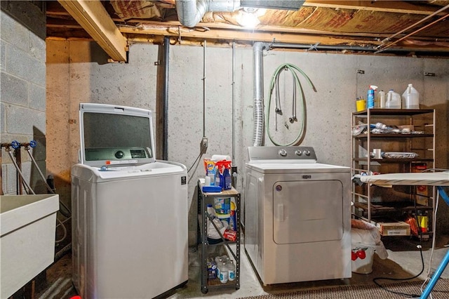 clothes washing area featuring washing machine and dryer, a sink, and laundry area