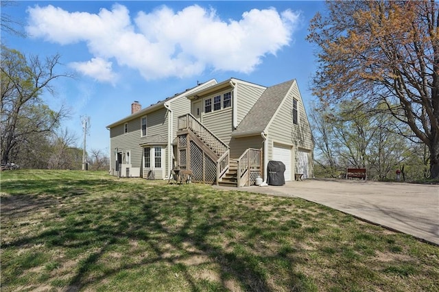 exterior space with a chimney, stairs, a yard, an attached garage, and driveway