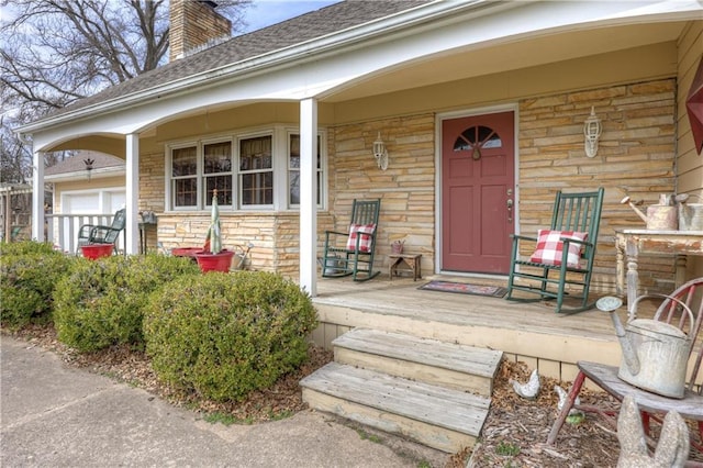 view of exterior entry featuring stone siding, covered porch, and a chimney