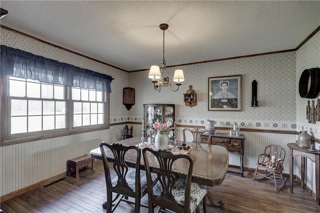 dining space featuring a textured ceiling, ornamental molding, and wallpapered walls