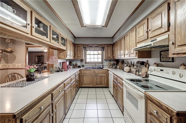 kitchen featuring under cabinet range hood, light countertops, light tile patterned flooring, white appliances, and a sink