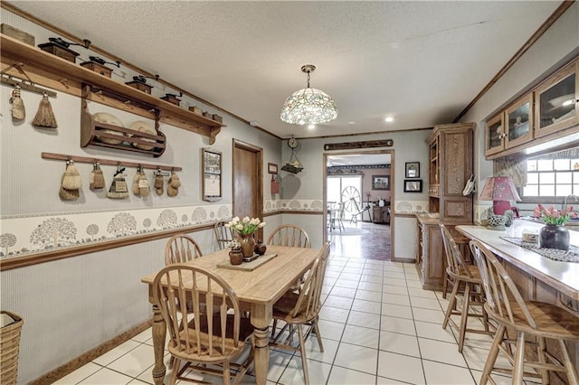 dining space featuring a textured ceiling, crown molding, a wealth of natural light, and wainscoting