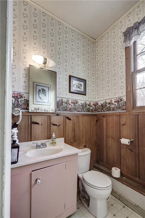 bathroom with wainscoting, wallpapered walls, vanity, and toilet