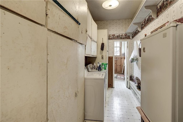 clothes washing area featuring wallpapered walls, washing machine and dryer, and light floors