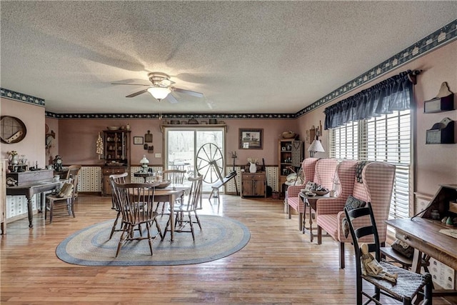 dining space with light wood finished floors, a textured ceiling, and ceiling fan