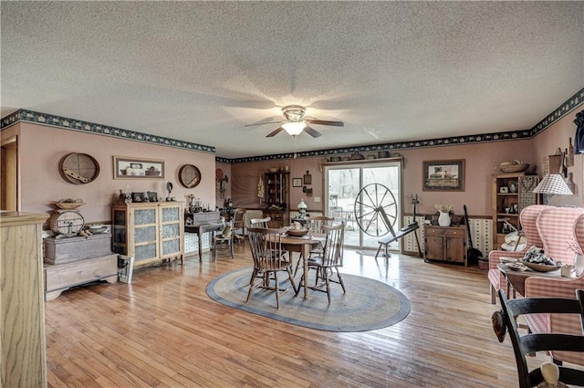 dining area with a textured ceiling, ceiling fan, and light wood finished floors