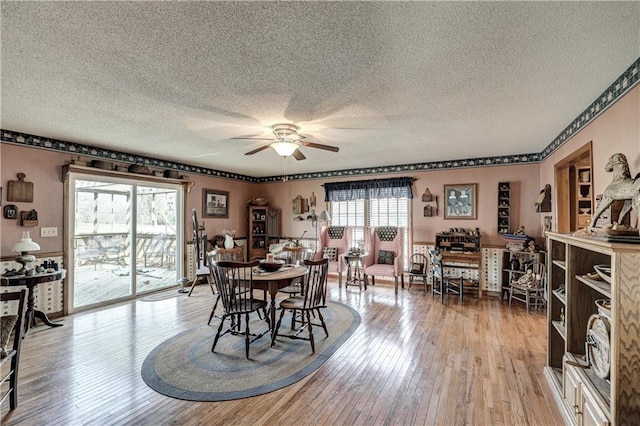 dining space with a textured ceiling, ceiling fan, and light wood finished floors