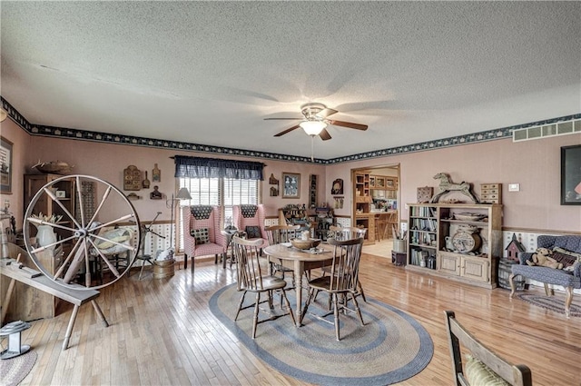 dining area with visible vents, a textured ceiling, a ceiling fan, and hardwood / wood-style flooring