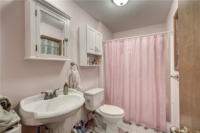 bathroom featuring tile patterned flooring, curtained shower, toilet, a textured ceiling, and a sink