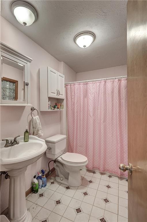 bathroom featuring curtained shower, a textured ceiling, and toilet