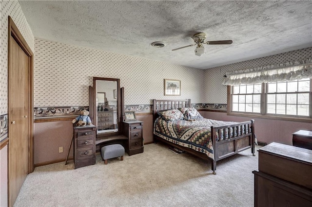 bedroom featuring a textured ceiling, visible vents, carpet, and wallpapered walls