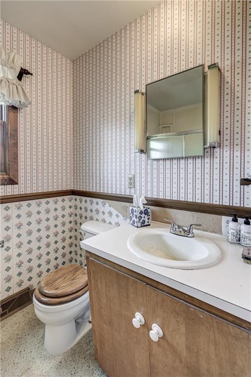 bathroom with visible vents, toilet, wallpapered walls, and vanity