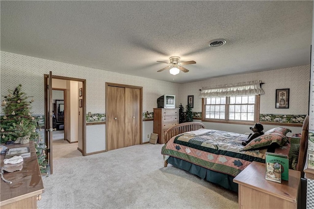 bedroom featuring a ceiling fan, carpet, visible vents, wallpapered walls, and a textured ceiling