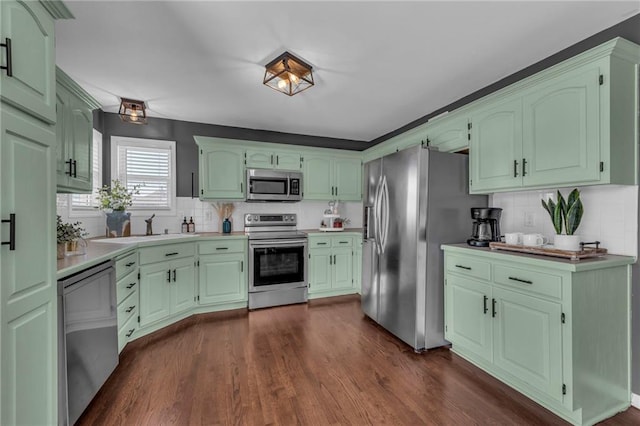 kitchen with a sink, dark wood-style floors, stainless steel appliances, light countertops, and decorative backsplash