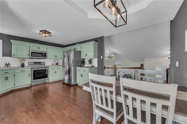 kitchen with dark wood finished floors, stainless steel appliances, light countertops, green cabinets, and a notable chandelier