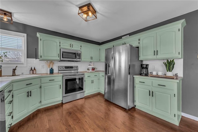 kitchen featuring dark wood-style floors, a sink, light countertops, appliances with stainless steel finishes, and backsplash