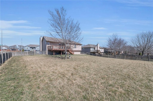 view of yard featuring a residential view, a deck, and a fenced backyard