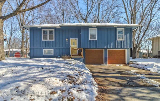 raised ranch with board and batten siding, concrete driveway, and an attached garage