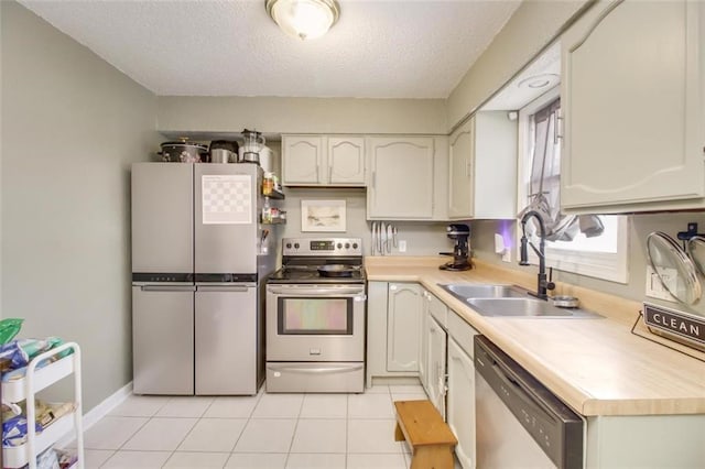 kitchen with a sink, appliances with stainless steel finishes, light tile patterned floors, and light countertops