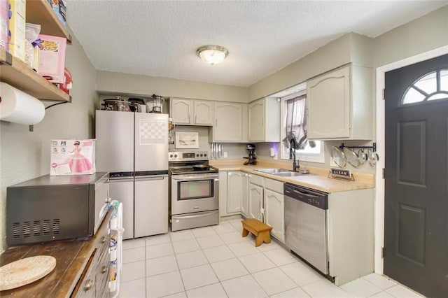 kitchen with a textured ceiling, stainless steel appliances, light countertops, and a sink