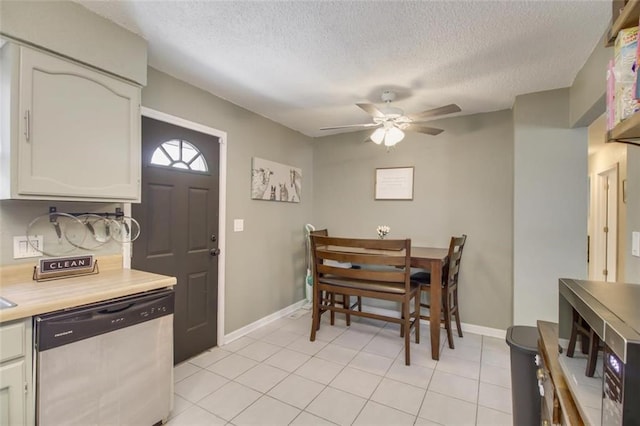 dining area with a textured ceiling, light tile patterned floors, baseboards, and ceiling fan