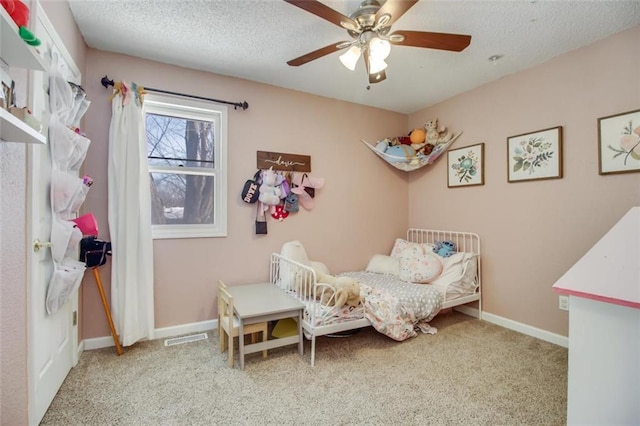 carpeted bedroom featuring visible vents, a ceiling fan, baseboards, and a textured ceiling