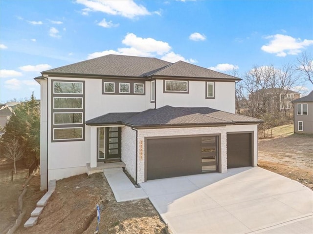 prairie-style home with stucco siding, concrete driveway, a garage, and roof with shingles