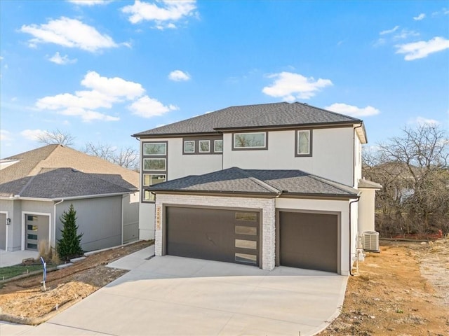 prairie-style home with concrete driveway, stucco siding, central AC, and roof with shingles