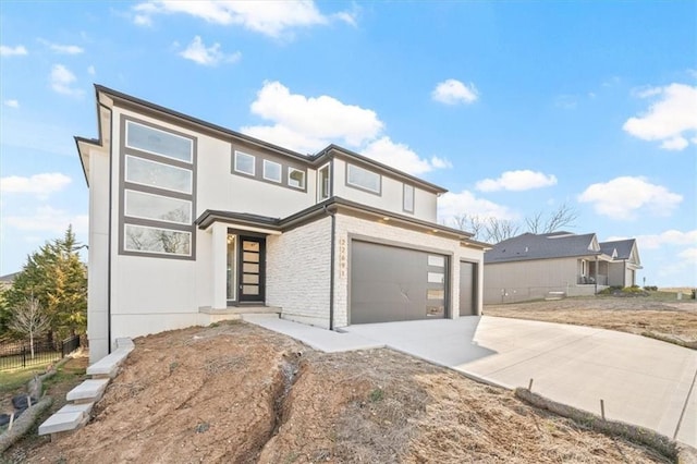 view of front facade with stucco siding, driveway, stone siding, fence, and a garage