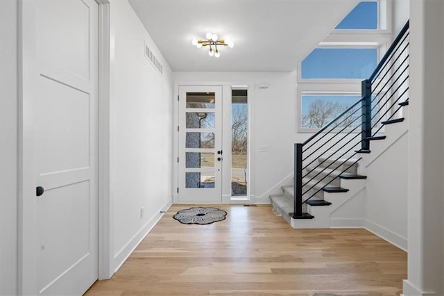 foyer with visible vents, baseboards, stairs, light wood-style floors, and french doors