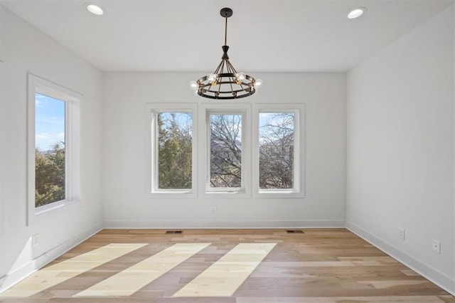 unfurnished dining area featuring light wood-style flooring, a notable chandelier, recessed lighting, and baseboards