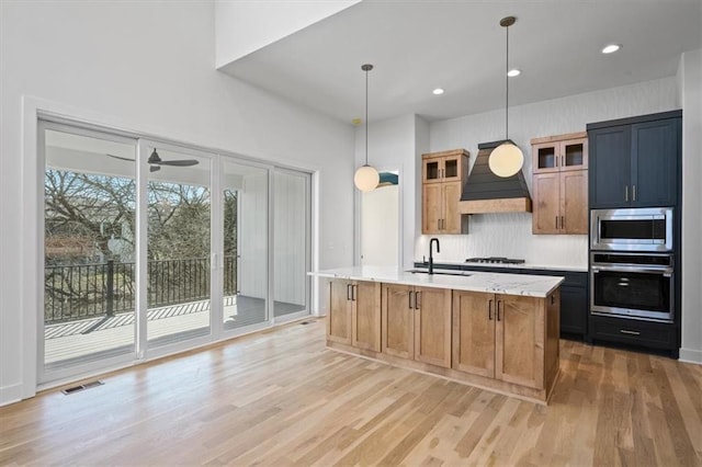 kitchen featuring light wood-type flooring, visible vents, a sink, stainless steel appliances, and custom exhaust hood