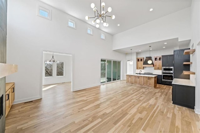 kitchen with custom exhaust hood, open shelves, light countertops, light wood-style floors, and a notable chandelier