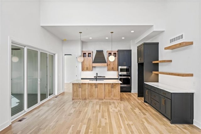 kitchen featuring light wood finished floors, visible vents, premium range hood, appliances with stainless steel finishes, and open shelves