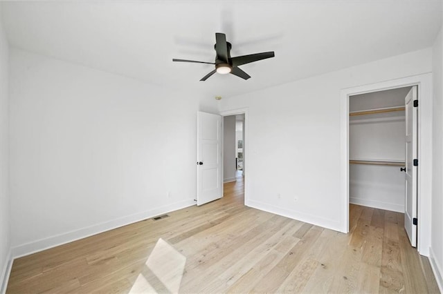 unfurnished bedroom with visible vents, baseboards, light wood finished floors, a spacious closet, and a closet